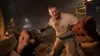 A first-person perspective of a fight scene in a dimly lit, rustic environment. Two men are engaged in combat, with one man in the foreground throwing a punch and another man in the midground reacting. Náhled obrázku produktu