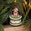 A small snow globe with a teddy bear inside, nestled among Christmas tree branches. Produktbild-Vorschau