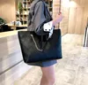 A person is holding a black tote bag in what appears to be a retail or office environment. Náhľad obrázku produktu