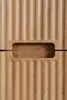 A close-up view of the ribbed texture and handle cutout of a wooden cabinet. Náhľad obrázku produktu