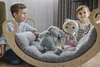 Two children are playing with toys on a wooden rocking horse with a cushion. Produktbild-Vorschau