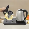 A hand is pouring tea from a glass teapot into a cup, next to an electric kettle on a heating plate. Náhled obrázku produktu