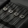 A close-up view of four metal skewers with flame-shaped emblems, neatly arranged in a black case. Produktbild-Vorschau