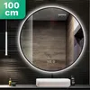 A round LED mirror is mounted on a wall with textured dark tiles. A white sink is below the mirror, and a pendant light hangs to the left. Produktbild-Vorschau