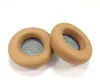 Two tan-colored ear pads for headphones are shown on a white background. Produktbild-Vorschau