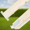 Two wooden beams are attached with metal brackets, set against a blurred background of green grass and a blue sky. Anteprima dell’immagine prodotto