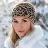 A woman wearing a leopard print headband and a white fur-lined jacket in a snowy environment. Produktbild-Vorschau