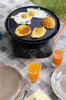 A camping grill with food and drinks on a table. Podgląd zdjęcia produktu