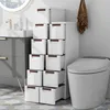 A bathroom with a toilet and a narrow cabinet filled with drawers next to it. Podgląd zdjęcia produktu