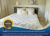 A bed with a white comforter and pillows, set in a bedroom. Produktbild-Vorschau