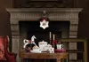 A festive Christmas display on a table in front of a fireplace, featuring decorative items. Náhľad obrázku produktu