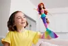 A young girl is holding up a mermaid doll in a brightly lit room. Anteprima dell’immagine prodotto