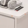 A close-up view of a white desk with headphones and pens on it. Produktbild-Vorschau