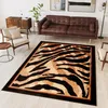 A living room scene with a brown leather sofa, a wooden cabinet, a chair, and a rug with a tiger pattern. Produktbild-Vorschau