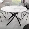 A round dining table with a marble-patterned top and a black metal base, surrounded by chairs in a dining room setting. Produktbild-Vorschau