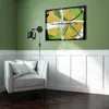 A wall-mounted lamp illuminates a chair and artwork in a room with green walls and white wainscoting. Náhľad obrázku produktu