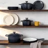 Various cookware items are displayed on wooden shelves against a textured wall. Produktbild-Vorschau