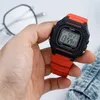 A hand holds a red and black Casio digital watch, with glasses and denim fabric in the background. Anteprima dell’immagine prodotto