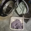 A white plastic basin with a purple towel sits on a gray floor next to an open washing machine with green towels inside. Anteprima dell’immagine prodotto