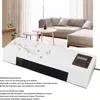 A white heater with a decorative butterfly design is placed in a living room setting with a sofa and coffee table in the background. Produktbild-Vorschau