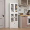 A white kitchen cabinet with glass doors and drawers, filled with various kitchen items, stands next to a closed door and a kitchen counter with appliances. Voir les images du produit