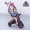 A young child is sitting in a pink tricycle with a canopy. Produktbild-Vorschau