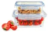 Two glass food storage containers stacked, one filled with cereal and the other with cherry tomatoes. Several cherry tomatoes are also placed in front of the containers. Produktbild-Vorschau