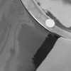 A close-up shot of a silver cylinder with a small white circular sticker on its rim. Produktbild-Vorschau