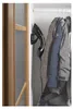 A handheld garment steamer is mounted on a wall inside a closet, next to hanging coats. Podgląd zdjęcia produktu