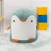 A plush penguin toy sits on a light blue rug in front of a white slatted wall. There are stacked colorful blocks to the right and a white bookshelf to the left. Produktbild-Vorschau