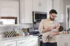 A man is feeding a baby in a kitchen. Náhled obrázku produktu