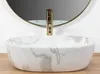 A close-up shot of a marble-patterned vessel sink with a gold faucet. Náhled obrázku produktu