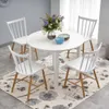 A round white dining table with four white chairs around it, set on a floral rug. Náhľad obrázku produktu