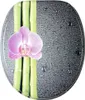 A toilet seat with a design of bamboo stalks and a pink orchid, with water droplets on a dark gray background. Produktbild-Vorschau