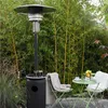 A patio heater and a small table with chairs are set up in a garden with bamboo in the background. Produktbild-Vorschau