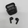 A black charging case and two black earbuds are placed on a white surface. Náhled obrázku produktu