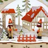 A wooden Christmas decoration depicting a winter scene with two figures and houses. Produktbild-Vorschau