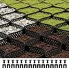 A close-up, angled view of a permeable grid system designed for landscaping, filled with gravel, soil, and grass. Produktbild-Vorschau