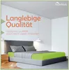 A bed with a green fitted sheet and gray bedding in a modern room. Produktbild-Vorschau