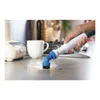 A hand is using a steam cleaner brush to clean a kitchen counter with coffee stains. Voir les images du produit