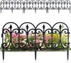A black metal garden fence with decorative scrollwork is shown in two configurations: one above the other. The lower fence is placed in front of a blurred background of pink and yellow flowers. Náhľad obrázku produktu