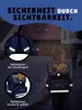 A child wearing a backpack walks on a street at dusk, with houses in the background. The image highlights the backpack's reflective features. Produktbild-Vorschau
