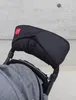 Close-up of a black stroller hand warmer attached to a stroller handle. Produktbild-Vorschau