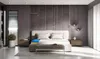 A bedroom scene with a mattress prominently displayed on a bed frame. The mattress has a cutaway section showing its internal layers. Produktbild-Vorschau