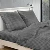 A close-up view of a bed with dark gray checkered bedding and pillows. Náhled obrázku produktu