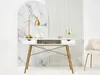 A white desk with gold legs and drawers, decorated with a gold lamp and other accessories, set against a marble-patterned backdrop and a fluted wall. Voir les images du produit