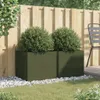 Two dark green planters with green bushes are placed on a lawn in front of a wooden fence. A chair is visible on the right side. Anteprima dell’immagine prodotto