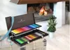 A wooden case of colored pencils is open, displaying rows of pencils, in front of a fireplace with a fire burning. Podgląd zdjęcia produktu