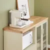 A cream-colored espresso machine is shown on a wooden countertop next to a framed picture. Below the countertop is a white microwave and a cabinet with glass doors. Voir les images du produit