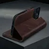A dark brown leather wallet case for an iPhone is shown in a studio setting, propped up in a stand position. Anteprima dell’immagine prodotto